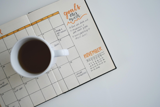 image of cup of coffee on top of a calendar on a table