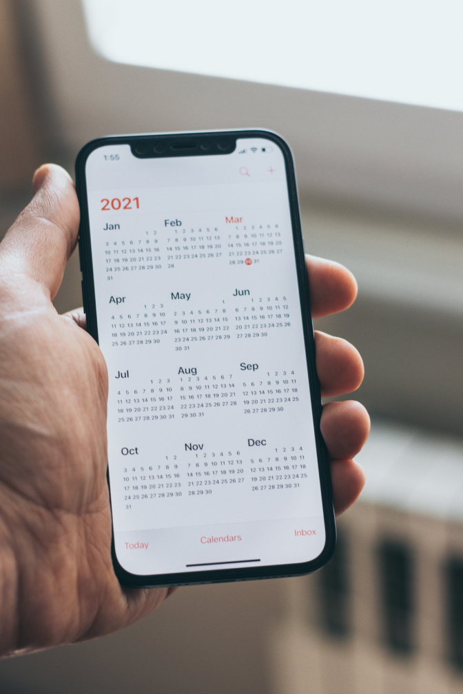 image of hand holding a smartphone with a calendar on the display